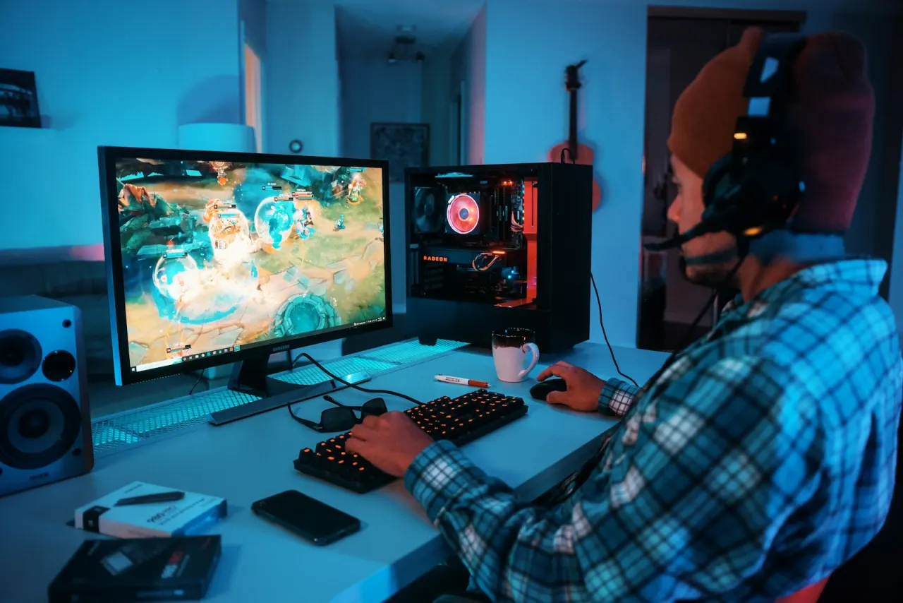 Kulaklık takmış bir oyuncunun neon ışıklı gaming istasyonunda oyun oynaması